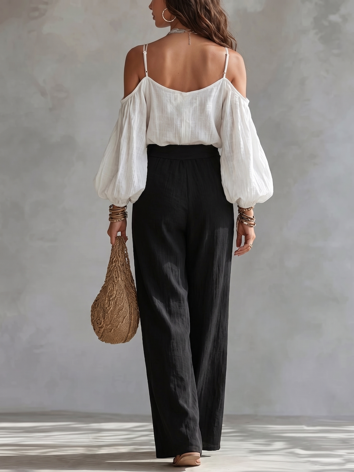 Conjunto compuesto por una camiseta sin mangas blanca con hombros al aire y unos pantalones negros de pierna ancha